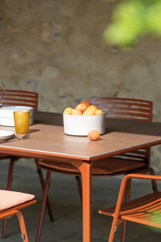 Allsize dining table with Snow stone top by FAST, paired with Ria dining chairs in Light Blue frames and Mint rope, styled with minimalist tableware and vases on a gravel surface.