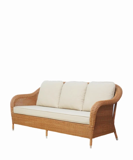 Angled view of the Riviera 3-seater sofa in honey synthetic wicker with beige cushions by Vincent Sheppard.