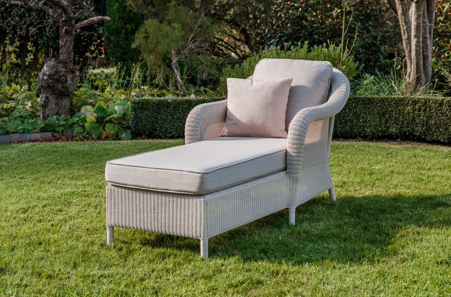 Vincent Sheppard Riviera daybed, also known as a chaise lounge, woven in Old Lace synthetic weave with plush cushions, set beside a side table.