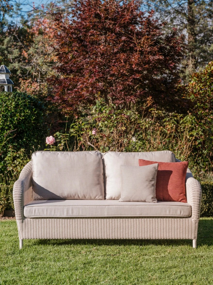 Riviera 2.5-seater sofa by Vincent Sheppard in synthetic weave, styled with terracotta and neutral pillows and a tray with drinks nearby.