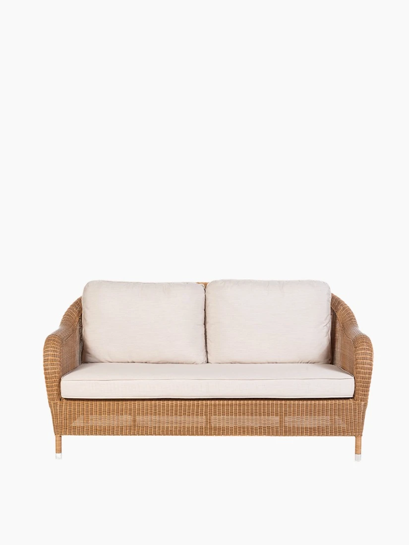 Riviera 2.5-seater sofa by Vincent Sheppard, featuring a Honey-colored synthetic rattan weave with light beige cushions and gently curved armrests.