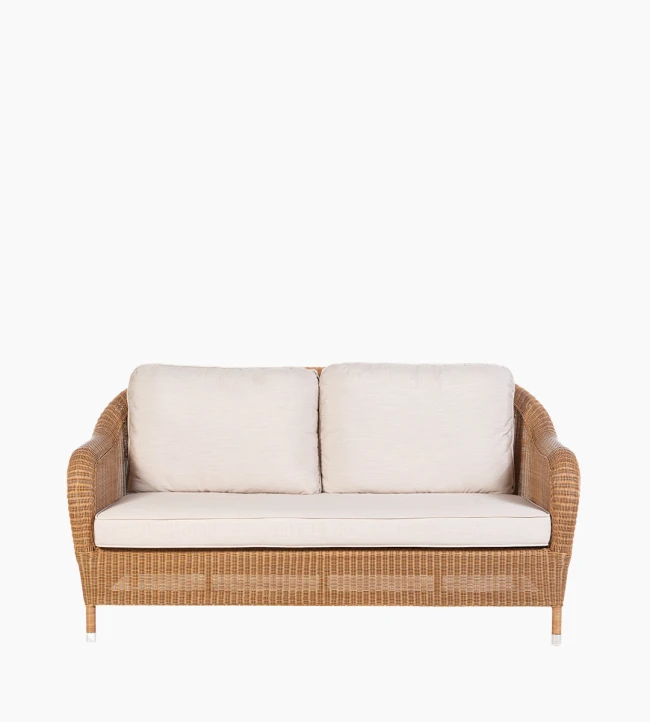 Riviera 2.5-seater sofa by Vincent Sheppard, featuring a Honey-colored synthetic rattan weave with light beige cushions and gently curved armrests.