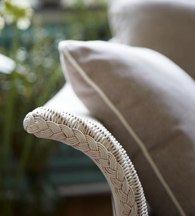 Close-up of a Victor sofa with a woven Snow Wash Lloyd Loom armrest and a Geneva Silver Grey cushion with piped edges.