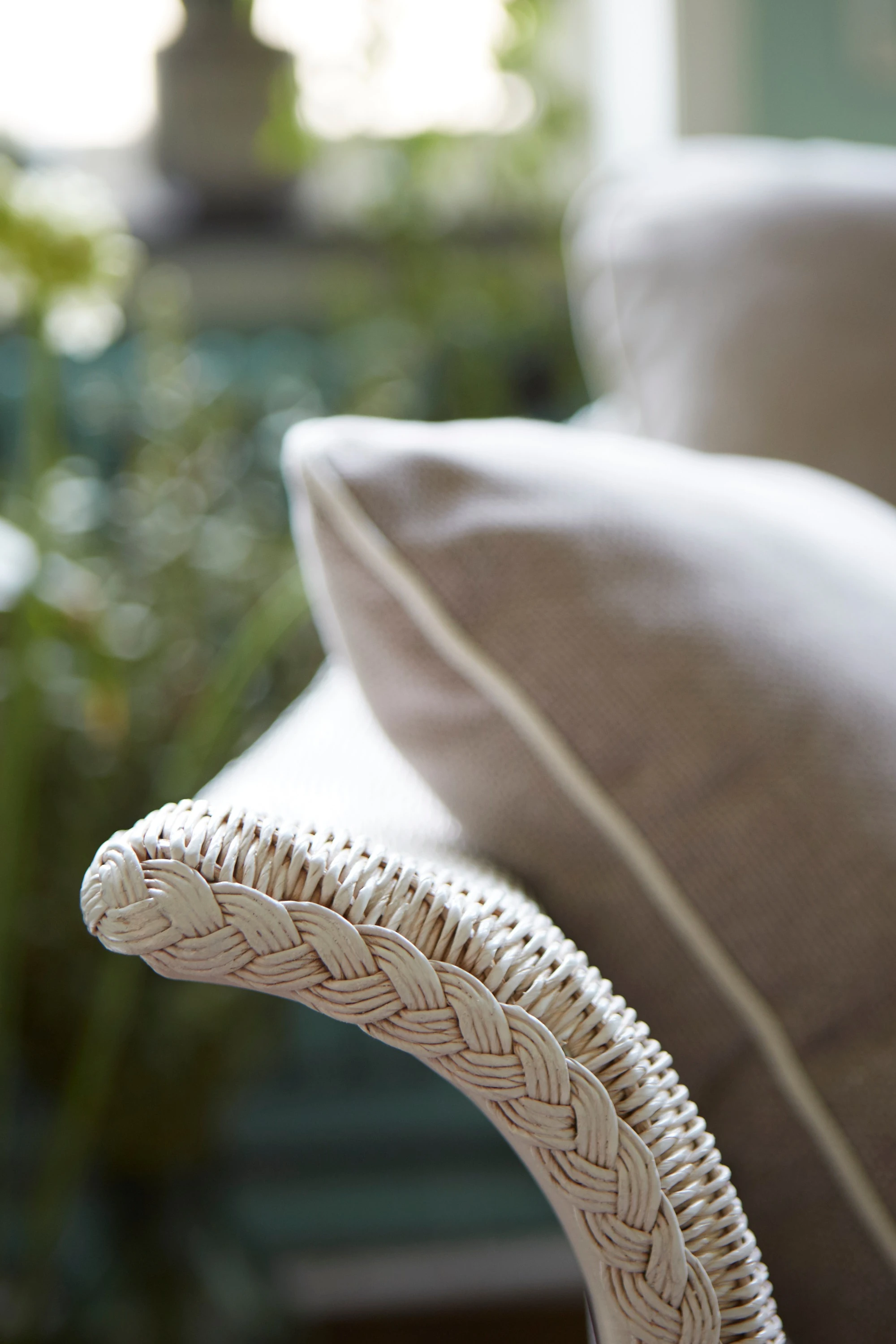 Close-up of a Victor sofa with a woven Snow Wash Lloyd Loom armrest and a Geneva Silver Grey cushion with piped edges.