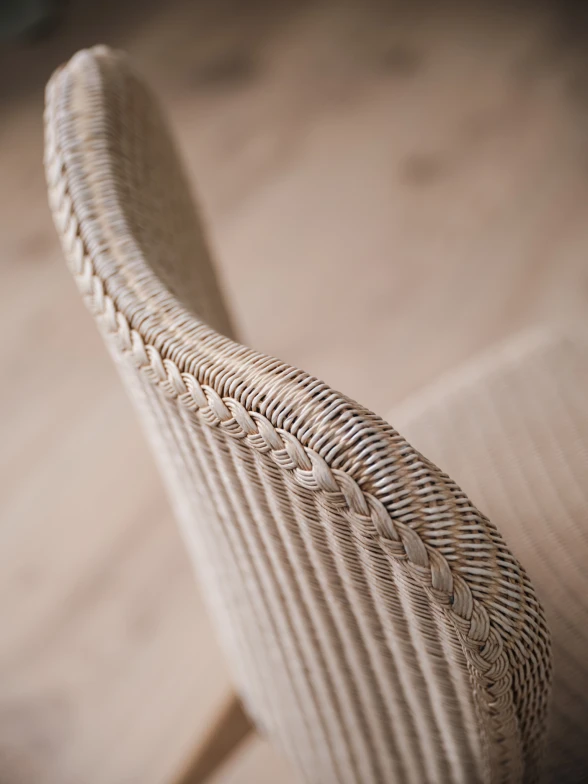 Close-up of a Lily Dining chair in Snow Wash Lloyd Loom, highlighting the curved backrest with vertical weaving and a braided edge detail.