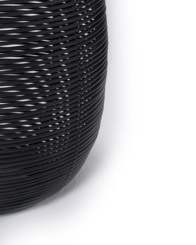 Close-up of the Tika lantern by Vincent Sheppard in black synthetic wicker, showing its tightly coiled, ribbed texture against a white background. The curved structure highlights the craftsmanship and modern aesthetic.