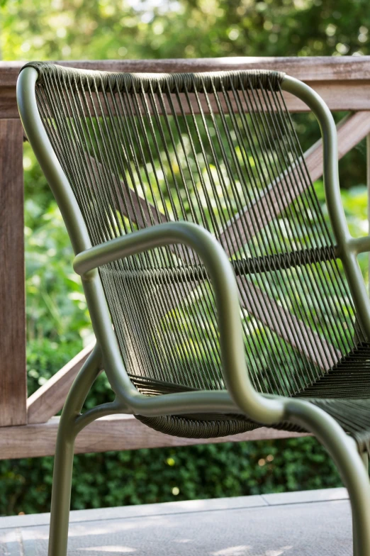 Close-up of the Loop Lounge chair in moss green by Vincent Sheppard, featuring a tubular metal frame and tightly woven vertical cord backrest and seat. 